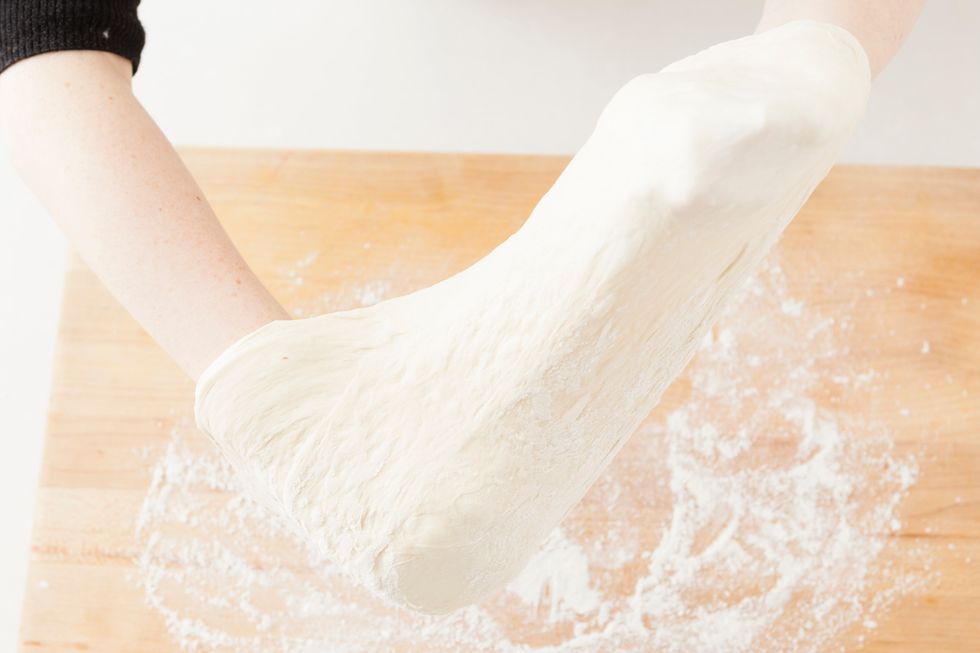 Stretch your dough to form your pizza crust. Sprinkle your workspace with flour to make it easier to handle. Set formed pizza crust on a pan lined with parchment paper and set aside.