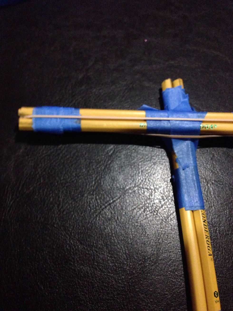 Stretch your rubber band between the gap of your horizontal pair of rubber bands. So it goes between the two erasers and the two unsharpened ends.