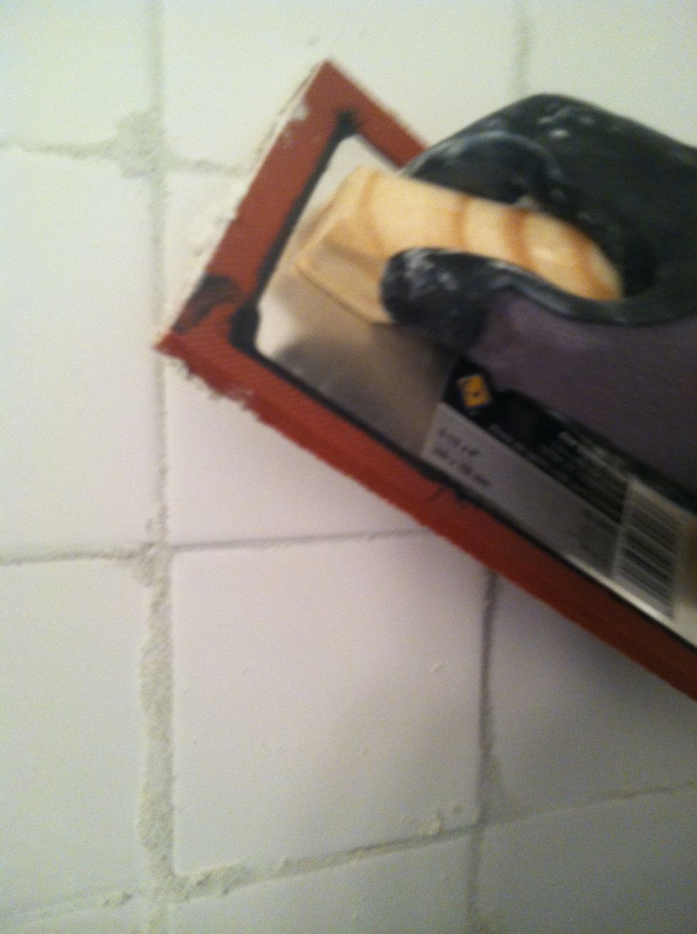 Strike tiles at about 45 degree angle and apply pressure as you drag (making sure the grout gets all the way into the space between tiles).