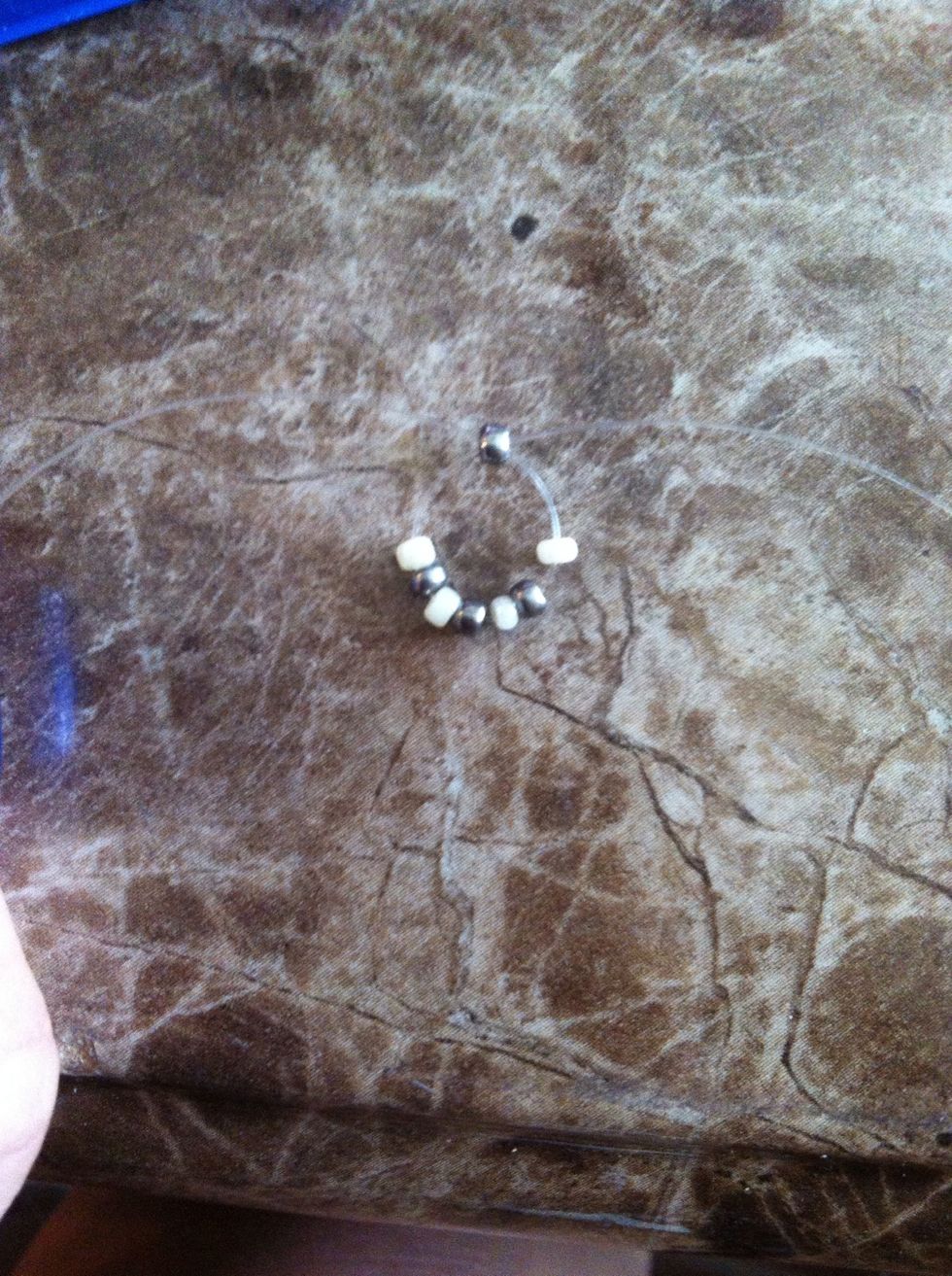 String a silver bead on one cord and cross through it with the other. Hold the two ends together to slide the beads down to the middle