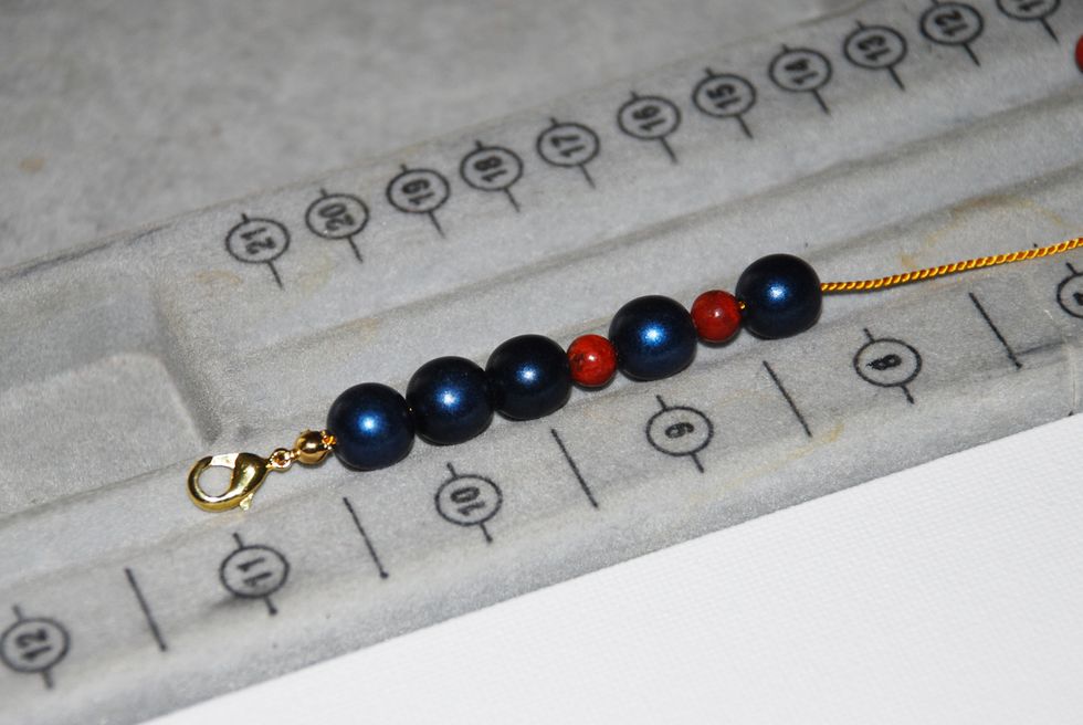 String all your beads onto the thread from one side to other, following the pattern on your tray. This helps to visualize the design before you start knotting.