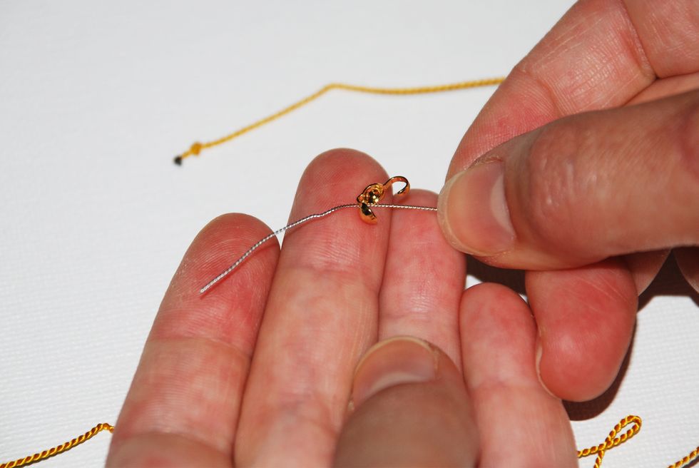 String one of your clamshell end-caps through the needle, with the hook of the cap facing in the direction of your end knot.