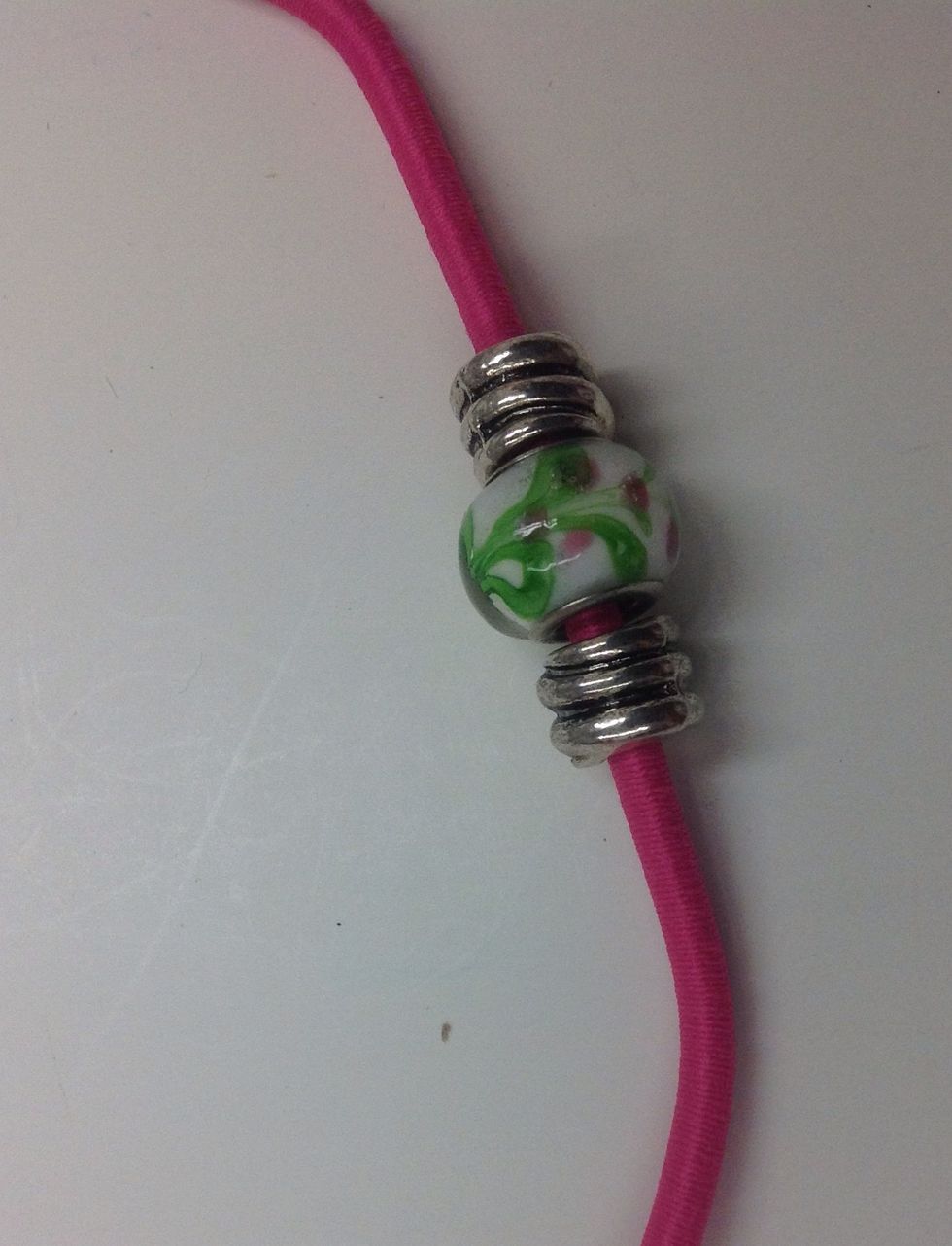String the beads on the bungee cord in a pleasing arrangement. If necessary, use the t-pin to help feed the cord through the bead.