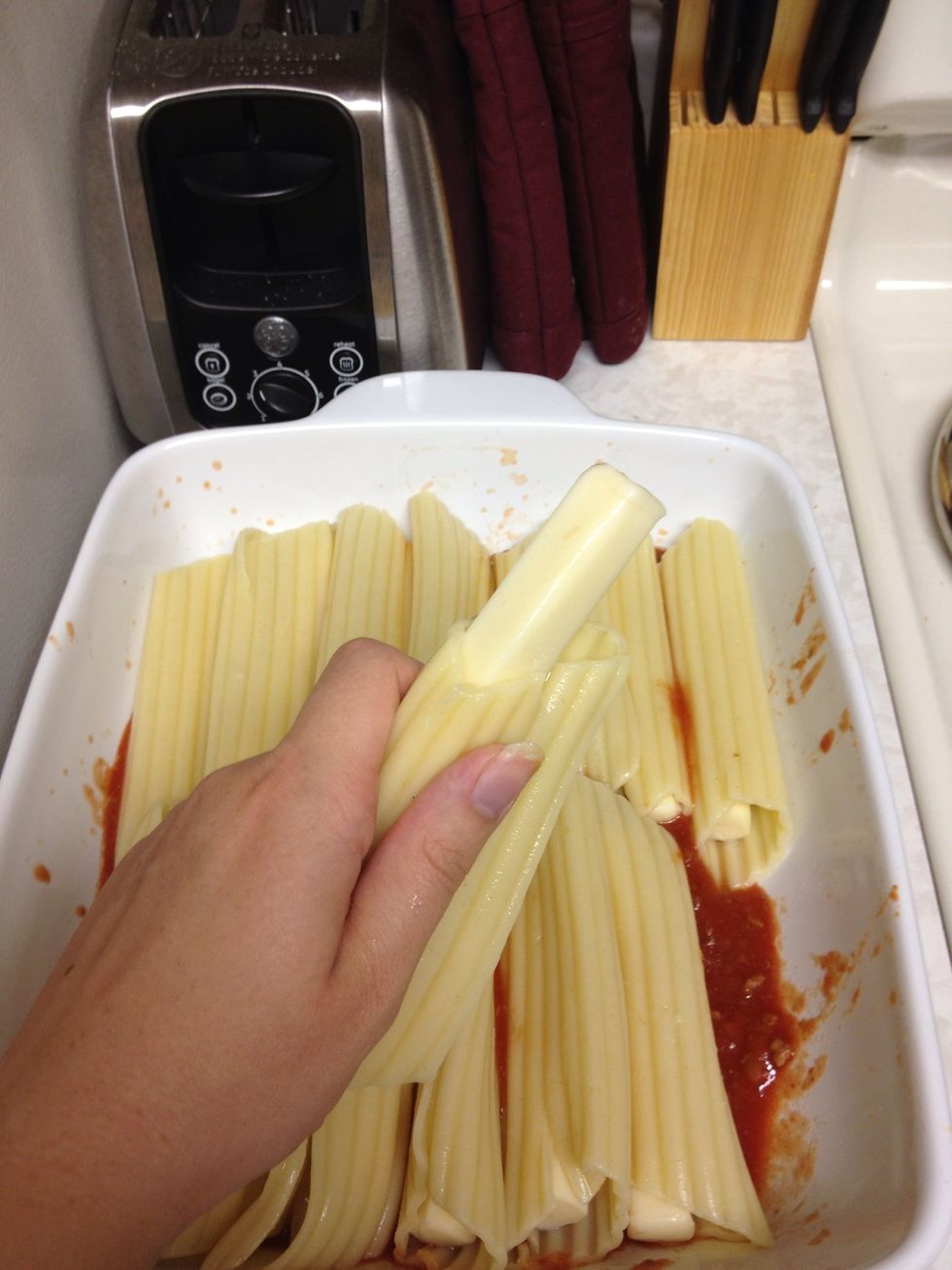 Stuff each noodle with a string cheese and place in the pan.