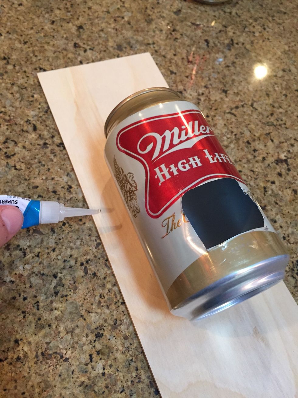 Super glue the can to the piece of wood