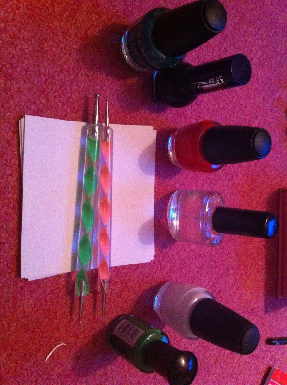 Supplies: white polish, green polish, red polish (or whatever colour of background you want), green sparkly polish (optional), black polish, clear polish, paper, dotting tools; varied in size.