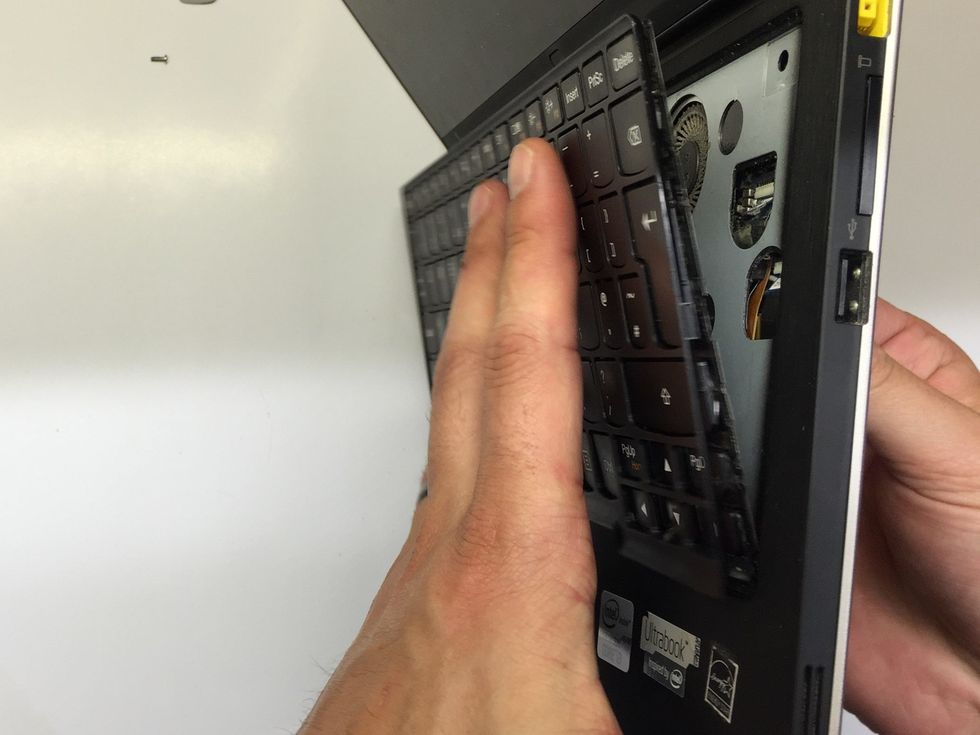 Support the keyboard as you push the paperclip through so it does not drop away from the chassis as it is still connected by a ribbon cable.