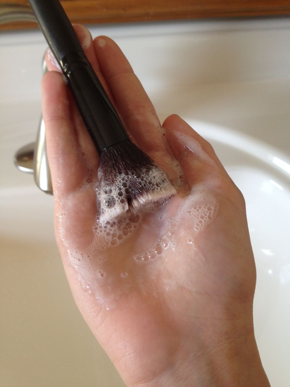 Swirl the tip of the makeup brush in the shampoo. Create bubbles in your hand, you should possibly see the bubbles turn the color of your powder. If that doesn't happen it's ok.