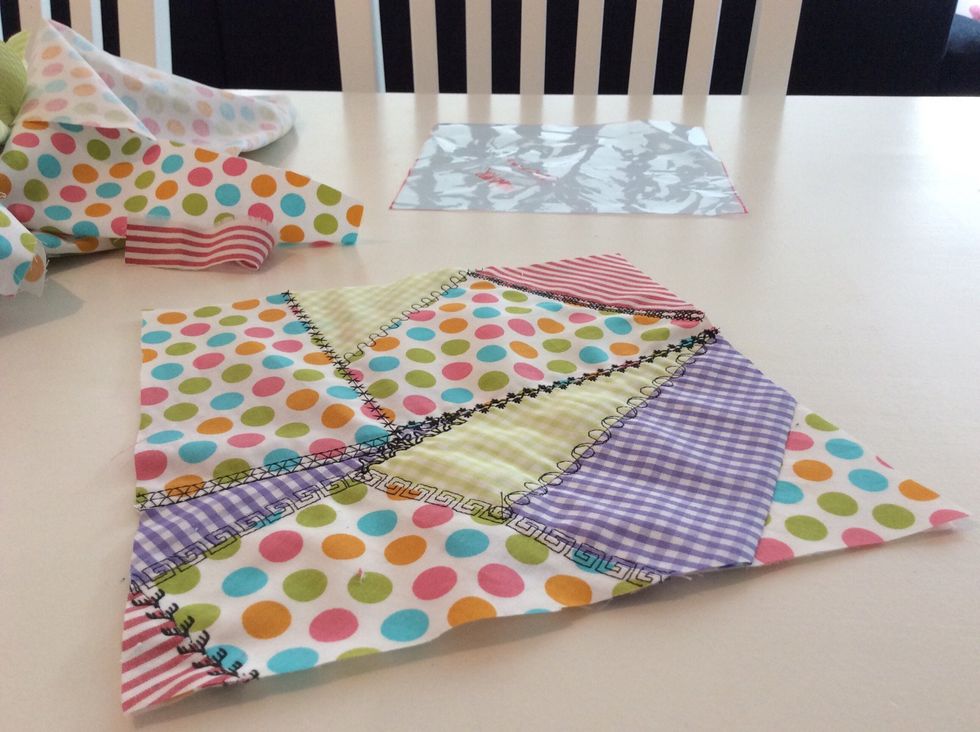Sy dekors\u00f6mmar \u00f6ver alla s\u00f6mmar samt \u00f6ver den r\u00e5a kanten. V\u00e4nd sedan din quilt upp och ner och klipp bort de m\u00f6nstrade tygerna som sticker ut utanf\u00f6r bastyget. Din quilt \u00e4r f\u00e4rdig.