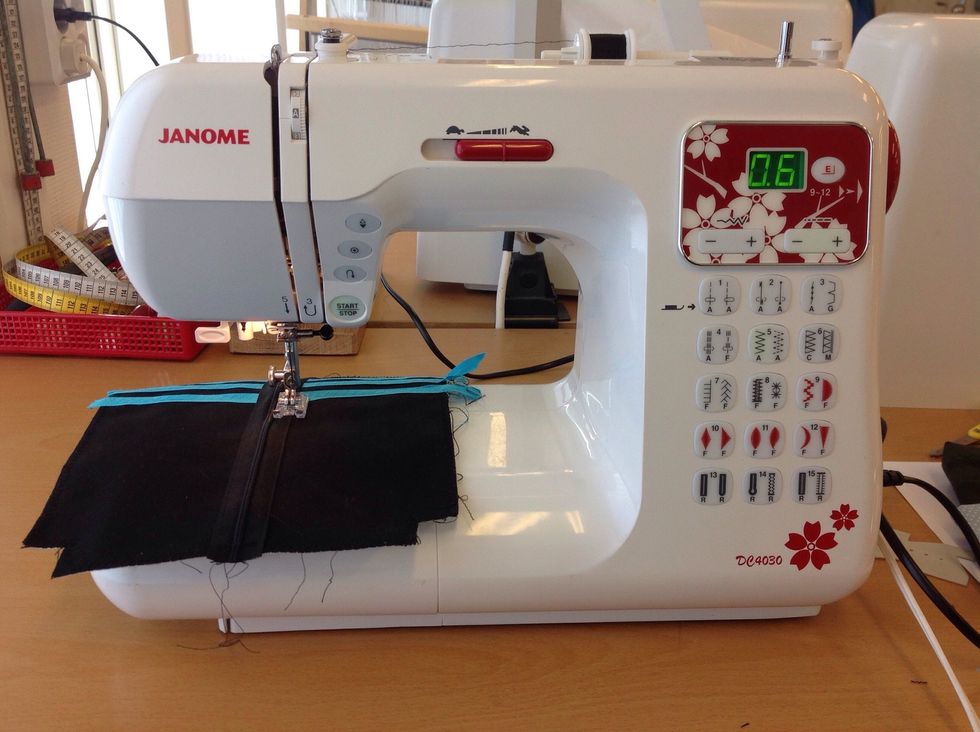 Sy sedan t\u00e4t sicksack \u00f6ver raks\u00f6mmen och kanterna p\u00e5 dragkedjan. V\u00e4lj s\u00f6m nummer 5 p\u00e5 symaskinen och minska stygnl\u00e4ngden till 0,6 genom att trycka p\u00e5 minus - p\u00e5 knappen uppe till h\u00f6ger.