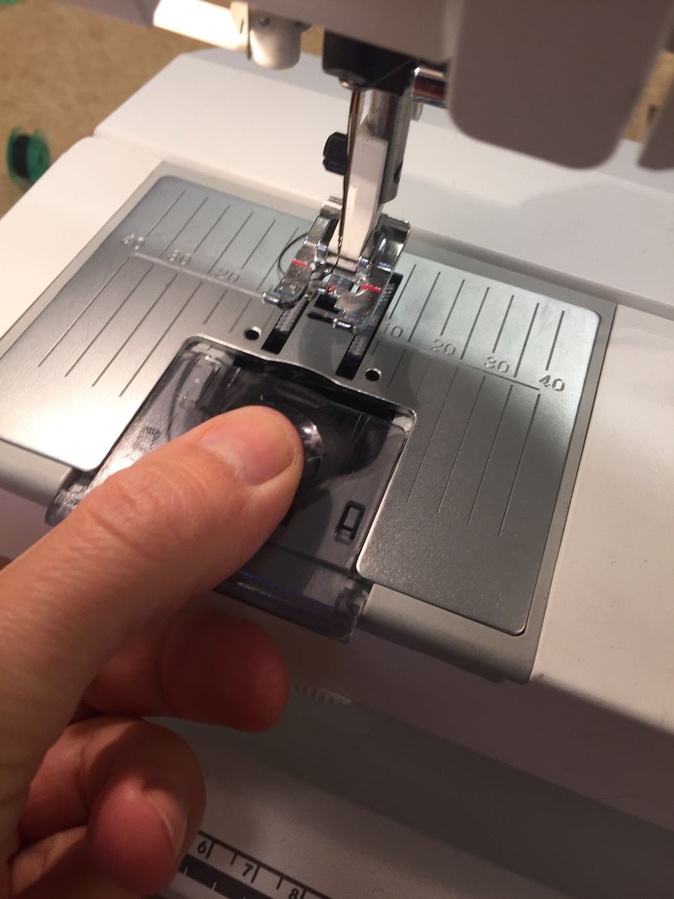 Ta bort brickan under pressarfoten. Dra den mot dig och tryck ner den samtidigt.