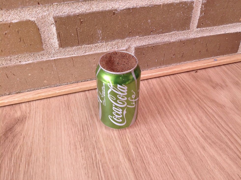 Ta bort ovandelen p\u00e5 burken med konserv\u00f6ppnaren. Packa sand i burken. Packa ganska h\u00e5rt f\u00f6r att undvika bucklor p\u00e5 burken n\u00e4r du g\u00f6r h\u00e5len.