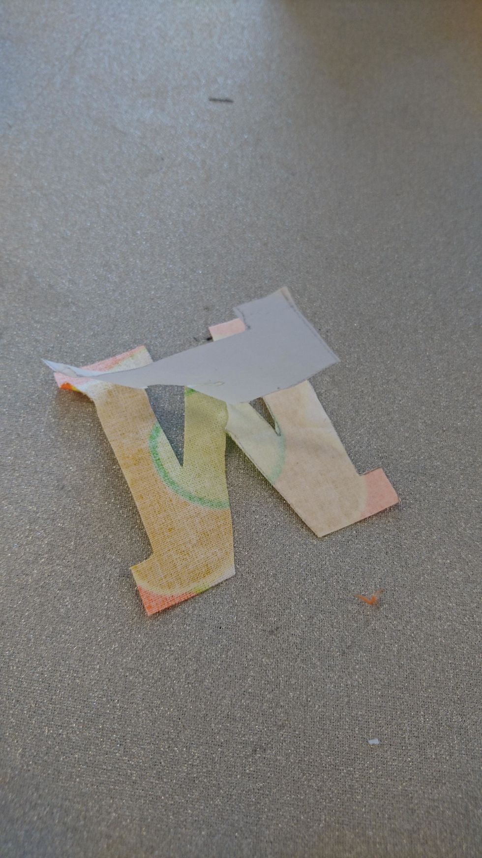 Ta bort pappret p\u00e5 avigsidan. Se till s\u00e5 klistret sitter kvar p\u00e5 tyget.