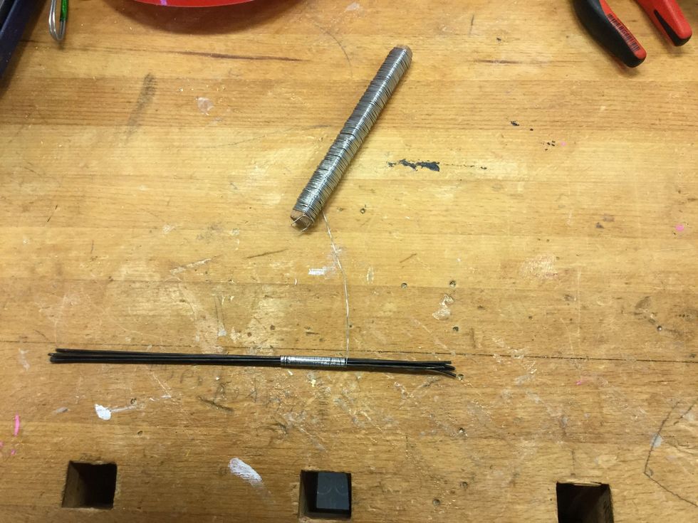 Ta fram den tunna tr\u00e5den och b\u00f6rja linda runt de fem tjocka tr\u00e5darna, s\u00e5 som bilden visar. Linda tr\u00e5den t\u00e4tt, och l\u00e5t inte tr\u00e5darna korsa varandra.