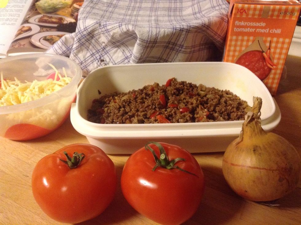 Ta fram k\u00f6ttf\u00e4rsen, tomater, riven ost och l\u00f6k. Take the meat, tomato, and onion.