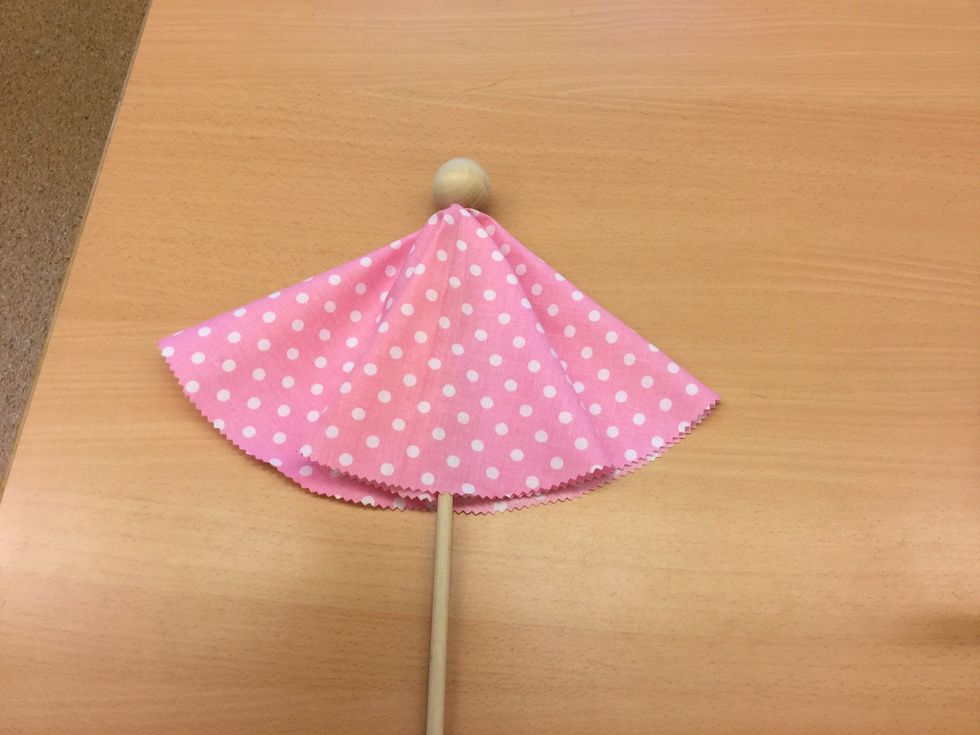 Ta fram rundstav och tr\u00e4kula. L\u00e4gg tyget p\u00e5 rundstavens ena \u00e4nde och tryck sedan fast tr\u00e4kulan,huvudet, ovanp\u00e5, s\u00e5 att det sitter fast ordentligt.