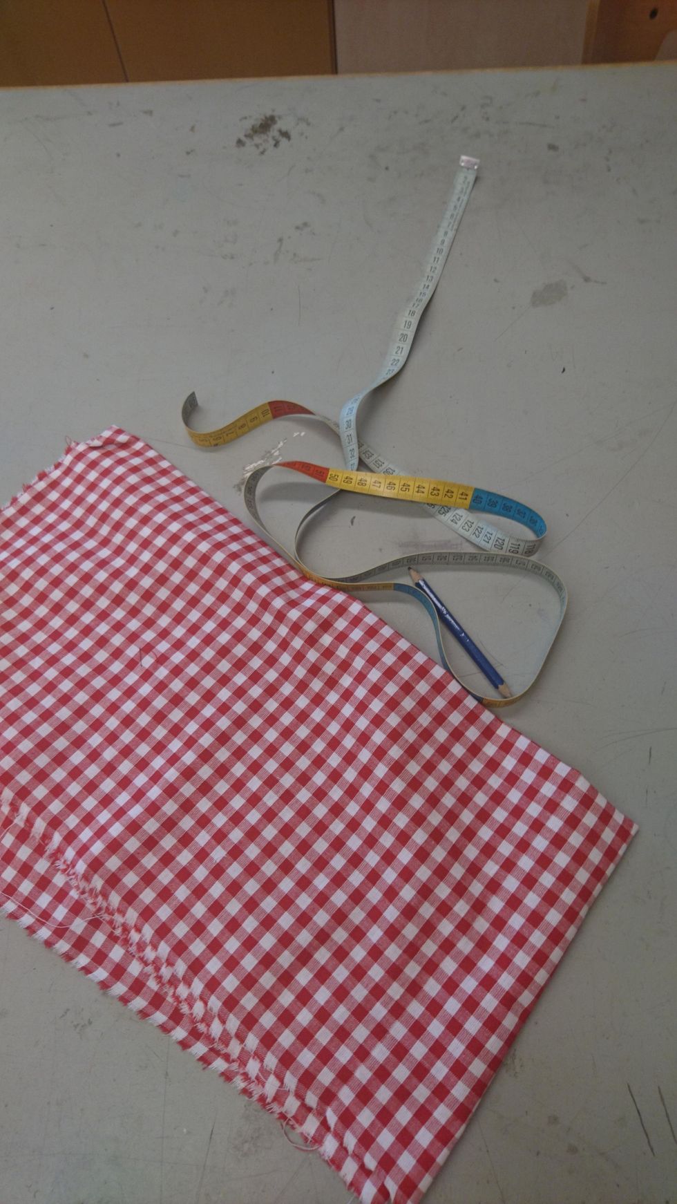 Ta fram rutigt tyg i valfri f\u00e4rg , m\u00e5ttband och en blyertspenna