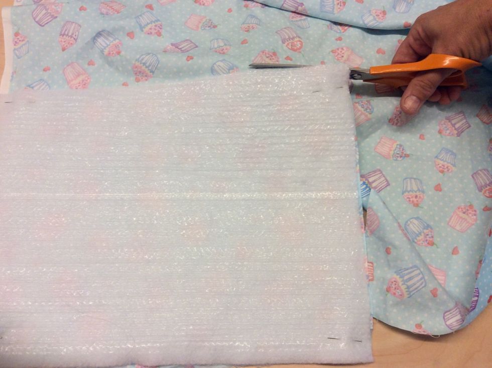 Ta mellantyget, n\u00e5la fast det p\u00e5 ett av tygerna med en n\u00e5l i varje h\u00f6rn. Klipp sedan ut ditt tyg lika stort som mellantyget.