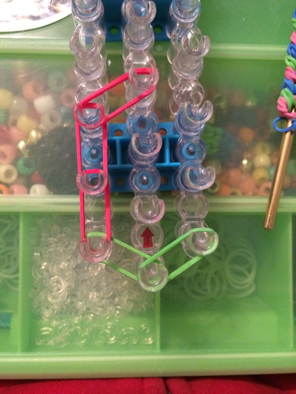 Take 2 more red bands and place them on the third peg on the left to the fourth peg in the center.
