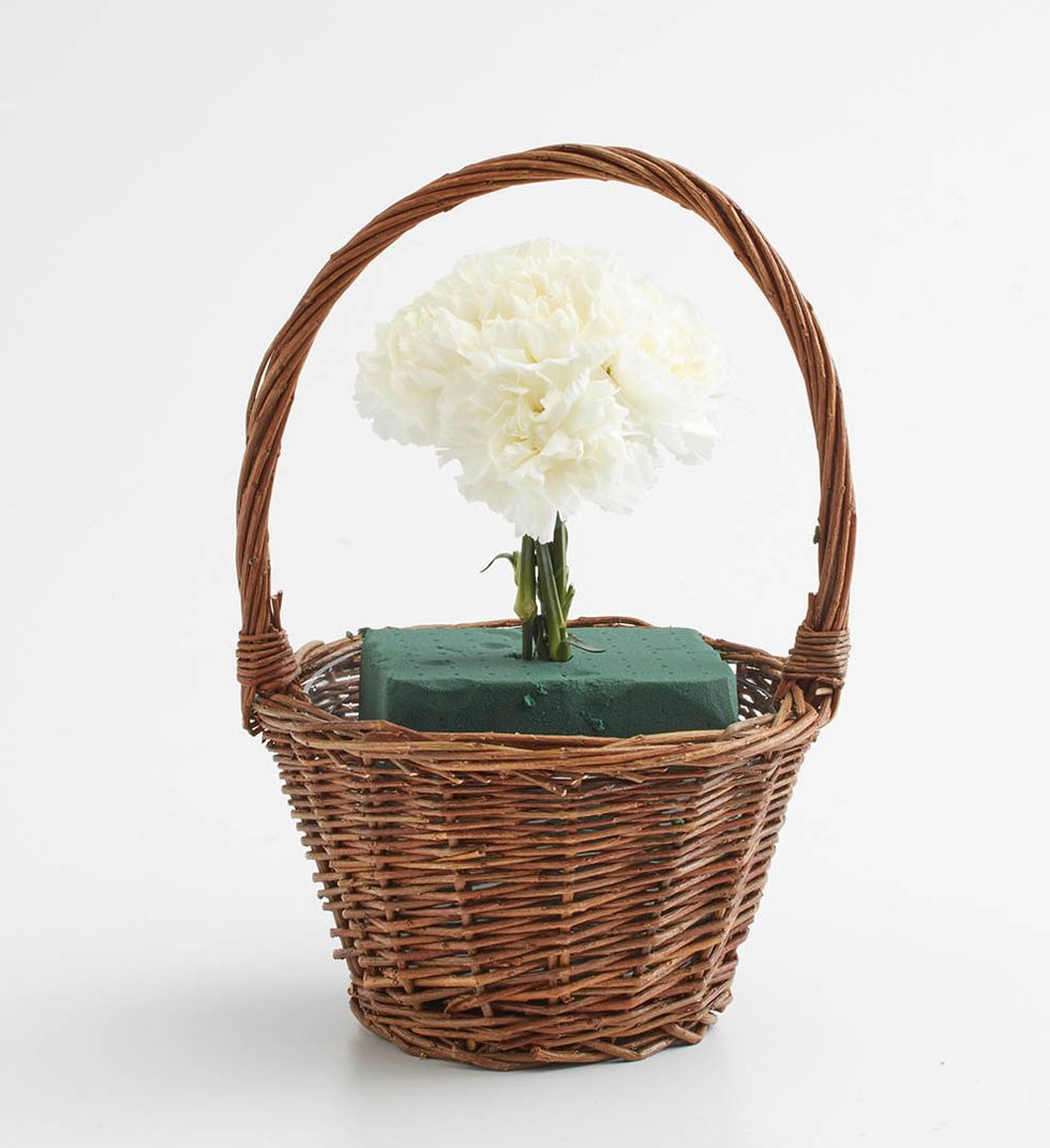 Take 5 carnations to create the face.  Using waterproof tape, tape them together.  This should create an oval/circular shape. Insert into floral foam.