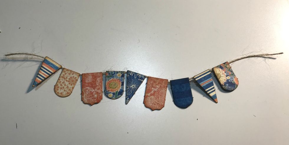 Take 9 banners off the banner sheet. Ink the edges of the banner using Vintage Photo Distress Ink and a blending tool with foam. Adhere the banners to a piece of twine.