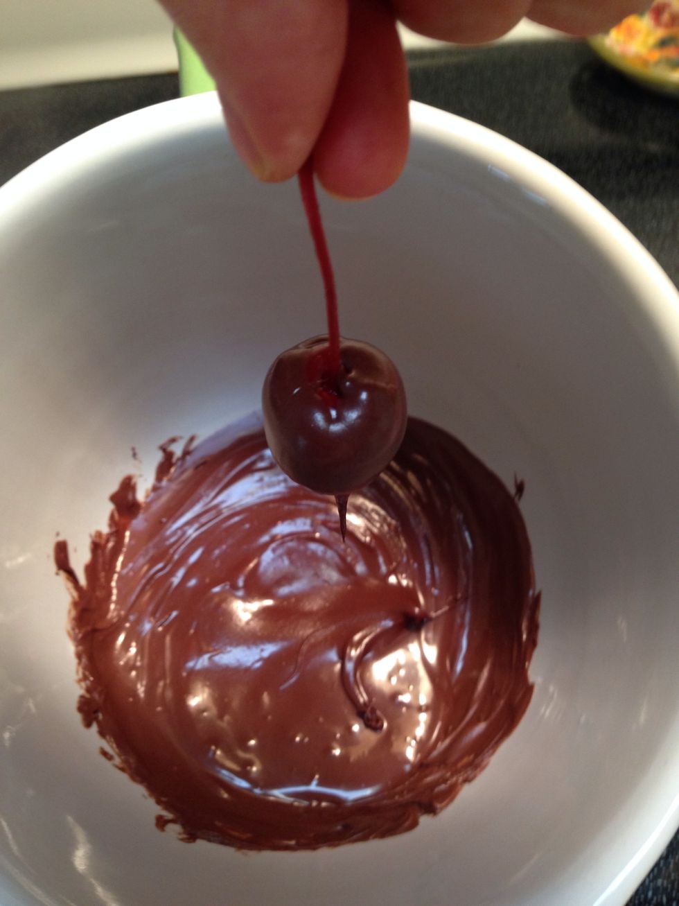 Take a cherry by the stem and swirl It in the chocolate coating it fully.