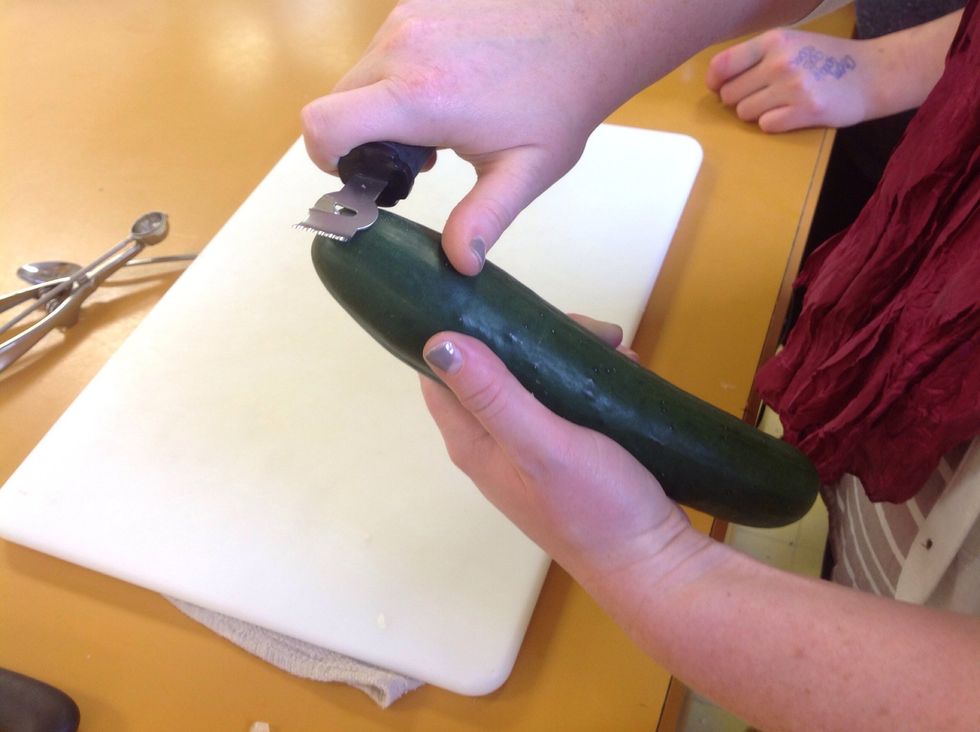 Take a cucumber and using the zester carve out a line down the length of the cucumber. Do this by slightly applying pressure to the zester the same way you would as if you were peeling it.