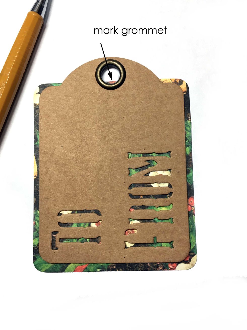 Take a Graphic 45 Staples ATC tag and mark where the grommet is on the design paper rectangle with a pencil.