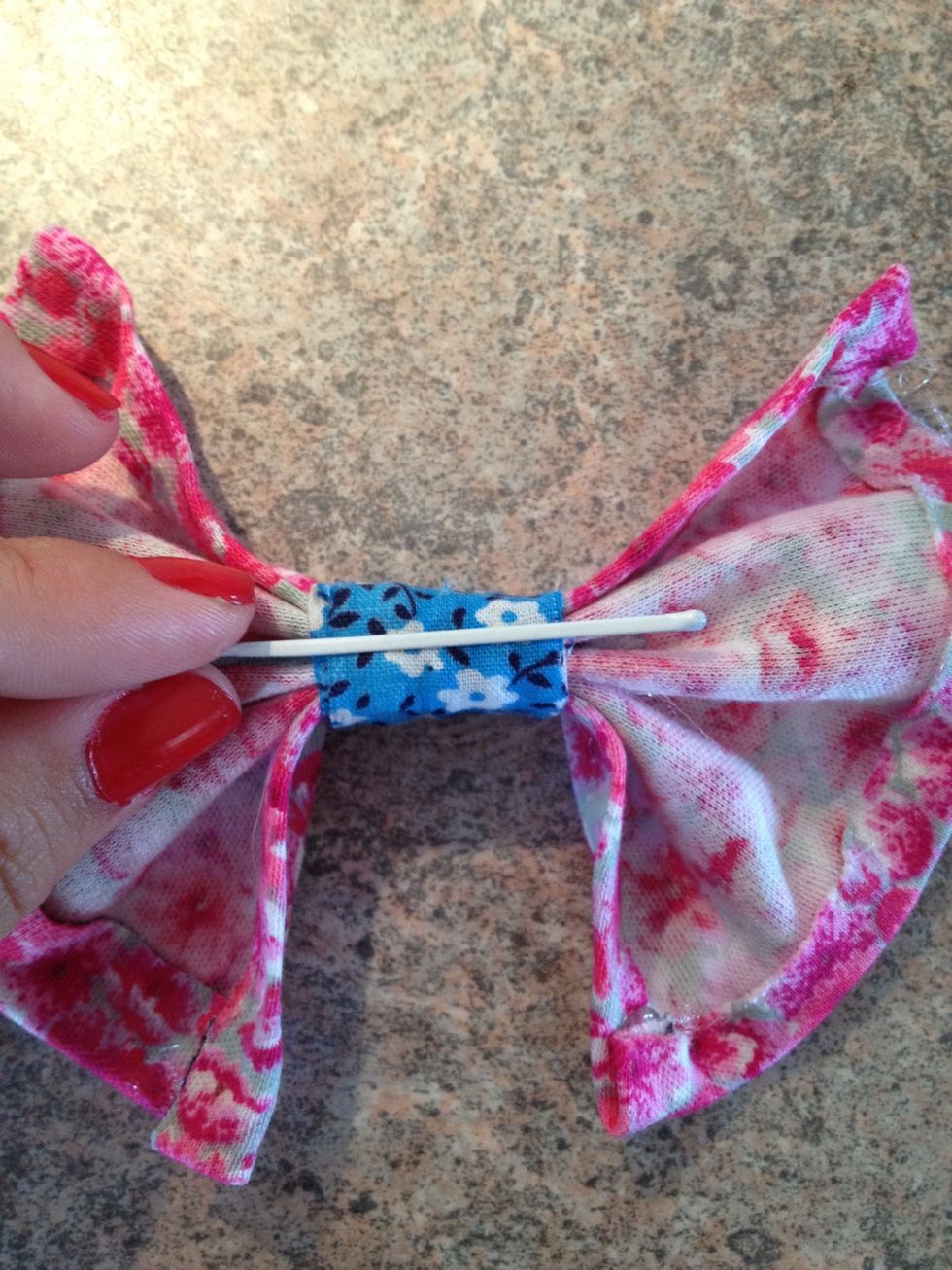 Take a hairpin, and put it under the other fabric that holds the bow together.