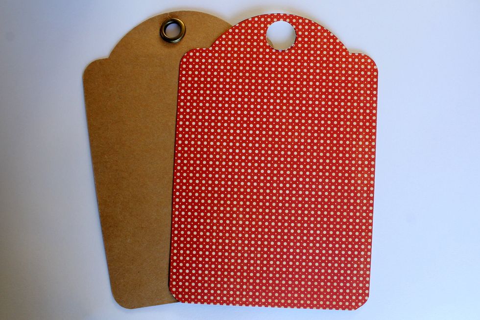 Take a kraft tag from the Regular Tag Album and cut the same form out of a red polka dot paper from the 8x8 Pad. Also cut out a hole of the same size as the hole in the kraft tag.