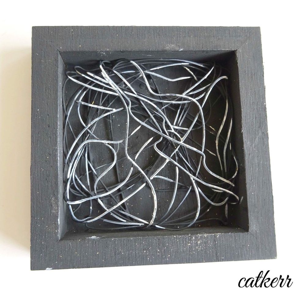 Take a large handful of wire and mold to fit the inside of the shadowbox. Glue in place with Tacky Glue. Spray the entire piece in black spray paint. Add gesso to some of the raised areas of the wire.
