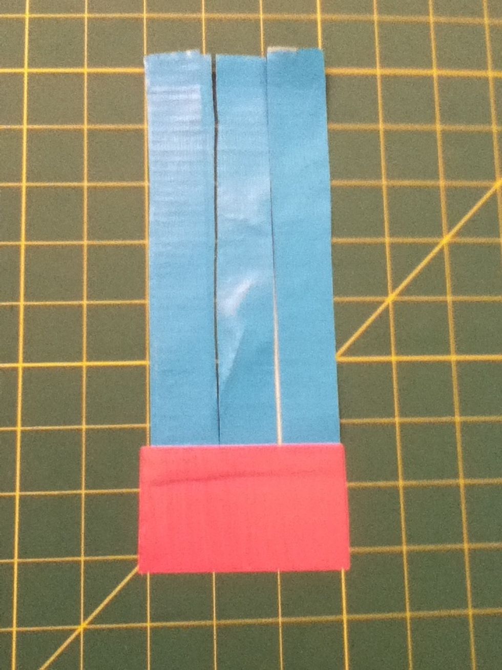 Take a peice of pink tape and tape just the end of the blue strips down to the mat.