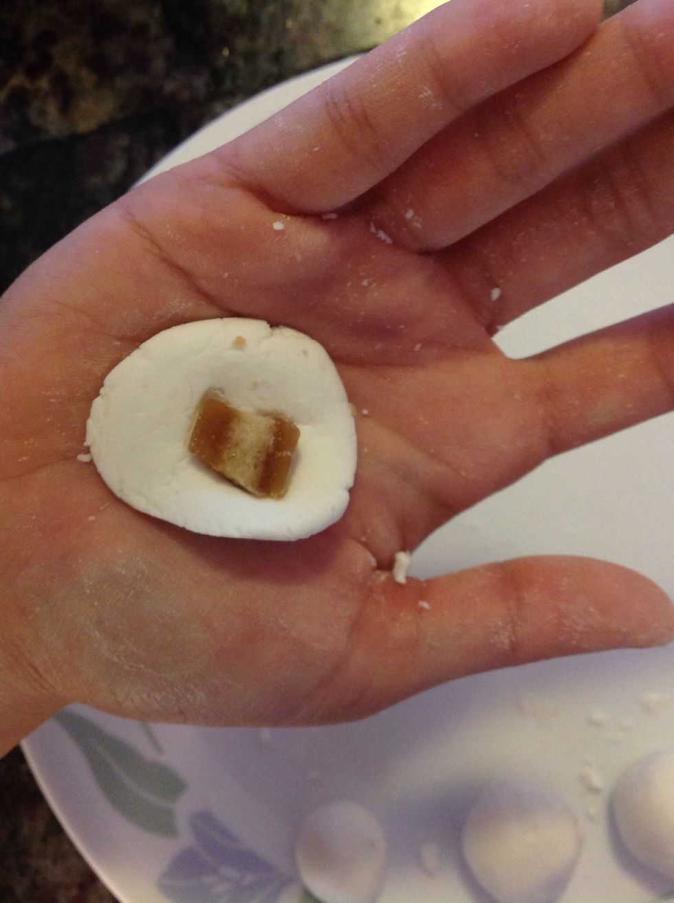 Take a pinch of the dough and flatten it, then place one of the cut sugar cube. Roll dough and cube until it is round and sugar is covered.