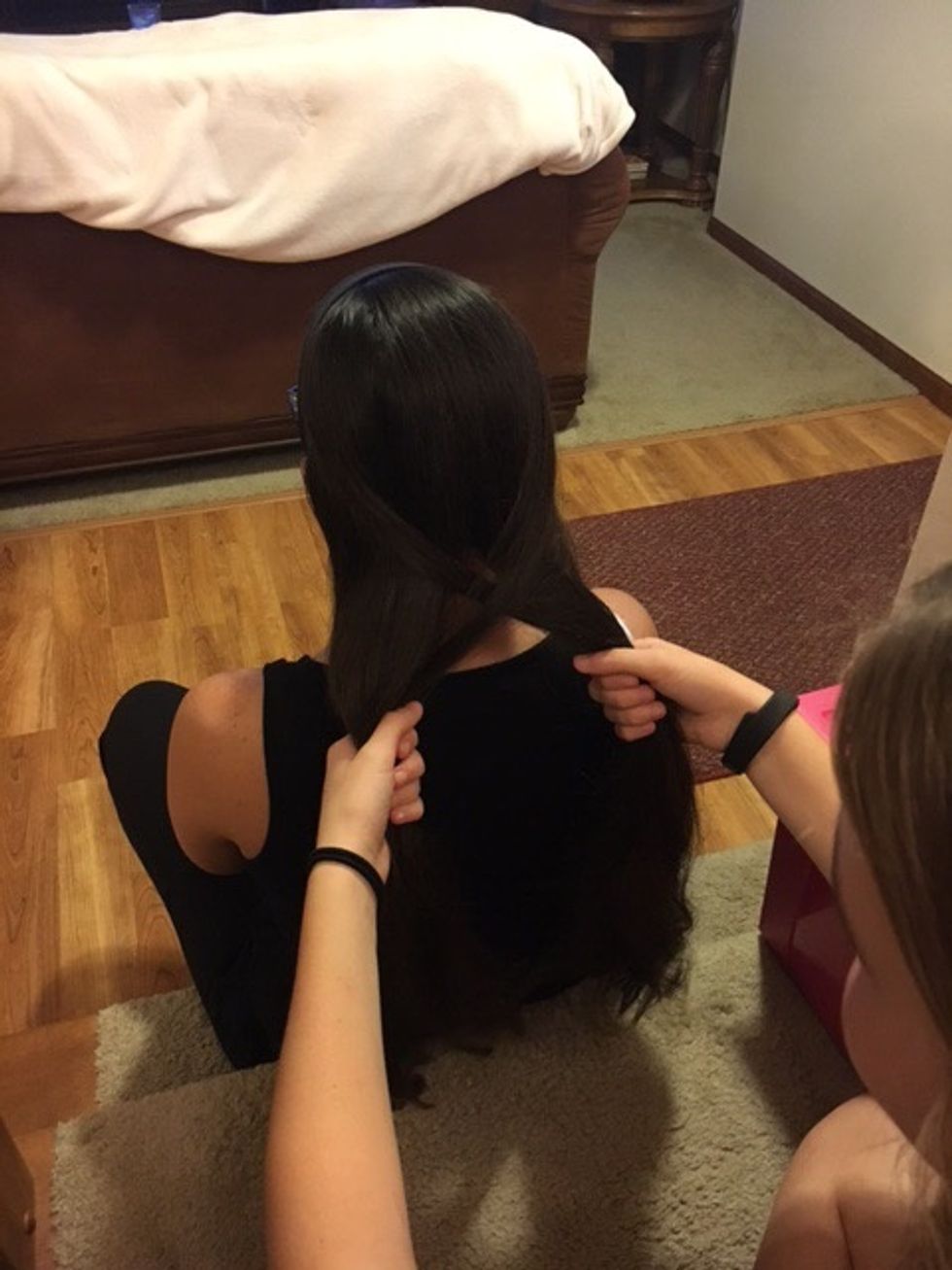 Take a small piece of hair from the far end of the left side and bring it over to the inside of the right half.