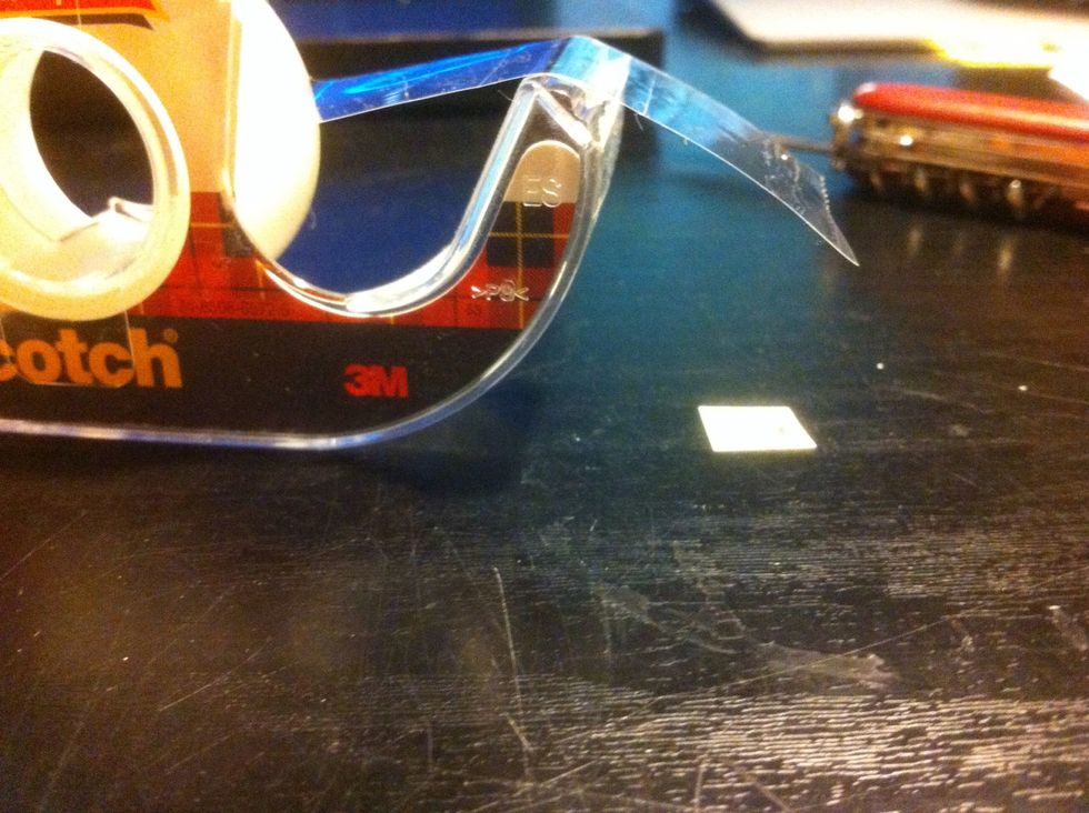 Take a small piece of tape and fold over an edge (so that it is easier to pull up). Put your cut out piece of paper on the tape and cut any extra tape off. Leave enough for it to stick though.