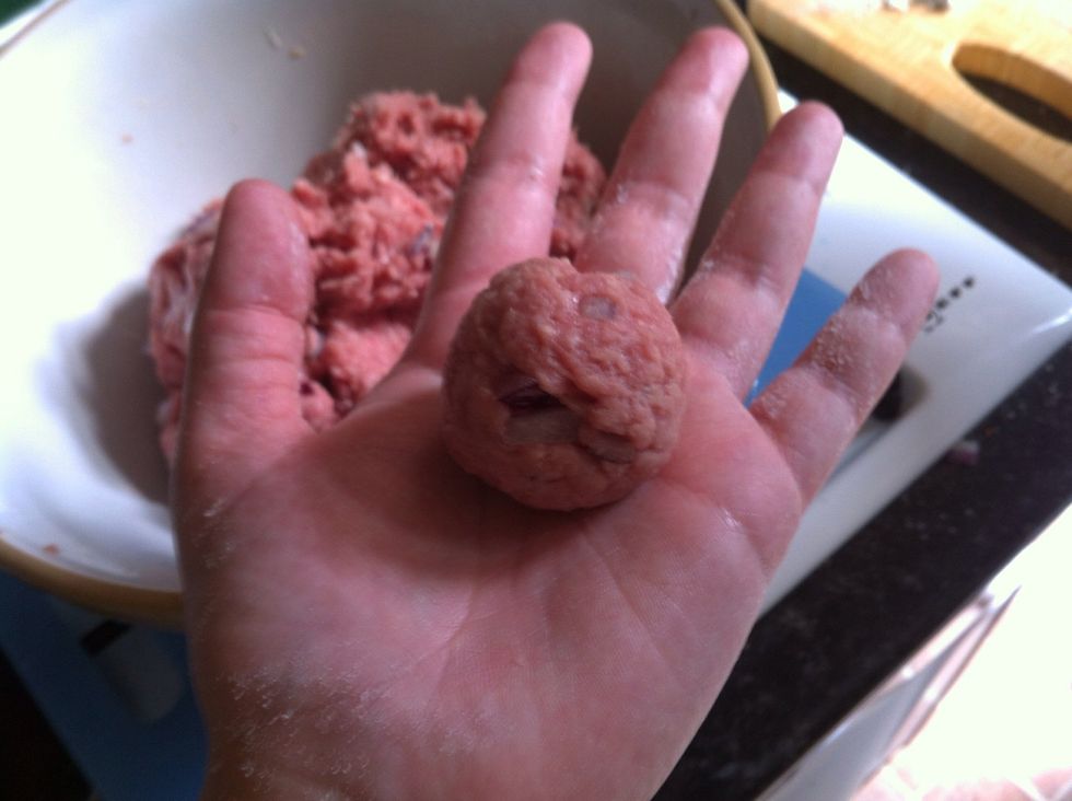 Take a small portion of the mixture, and place a pinch of flour on your palm. Roll it together to make a small ball like this.