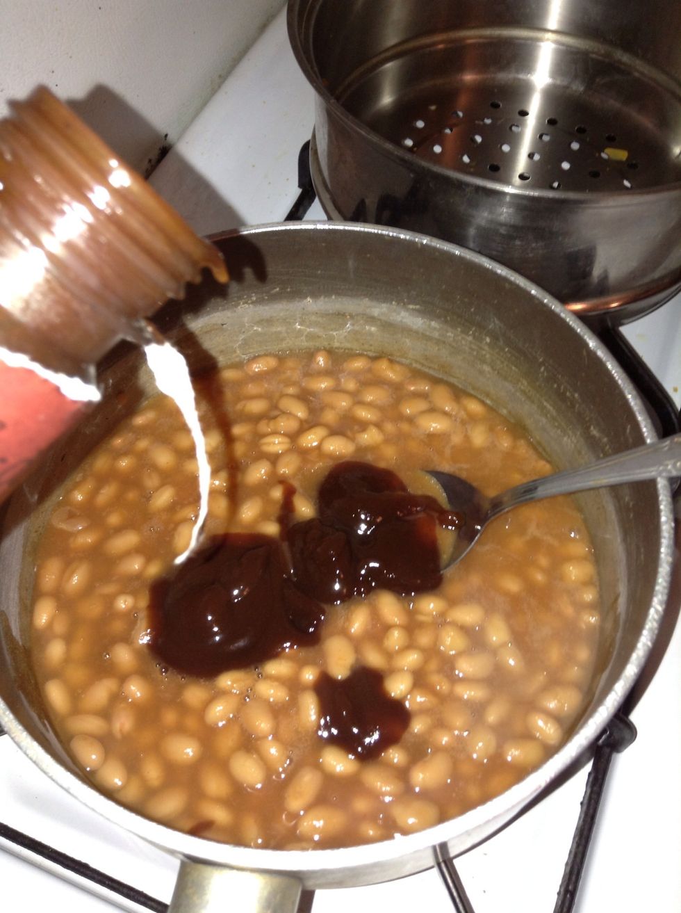 Take a step away from the potatoes for a minute and add the  green seasoning , ketchup, honey, vinegar, mustard, barbecue sauce, black pepper, a dash of Sazon to the baked beans...