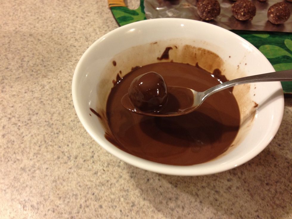 Take a truffle and dunk it into the melted chocolate. Let the excess chocolate drip off. It's probably a good idea to use a fork instead of a spoon.