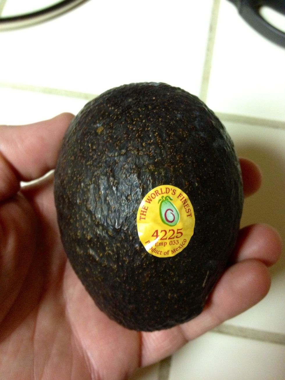 Take an avocado and slice it neatly in half to reveal the meat and the seed (or pit).