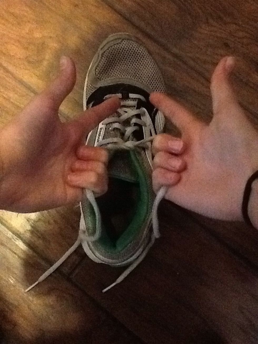 Take both hands and form a 'hand gun' around the laces.