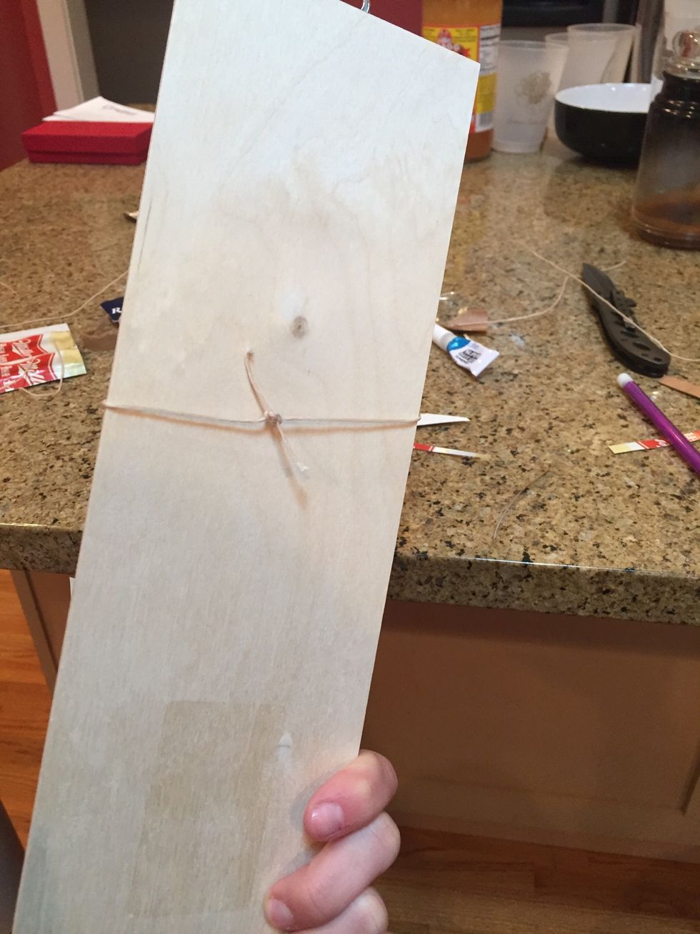 Take both pieces of string and tie a knot in the back