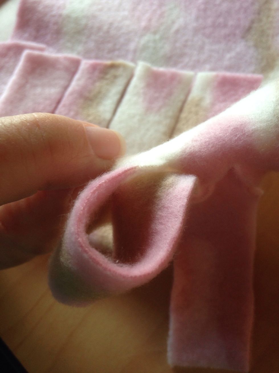 Take edge of each fringe and loop it through each slit.