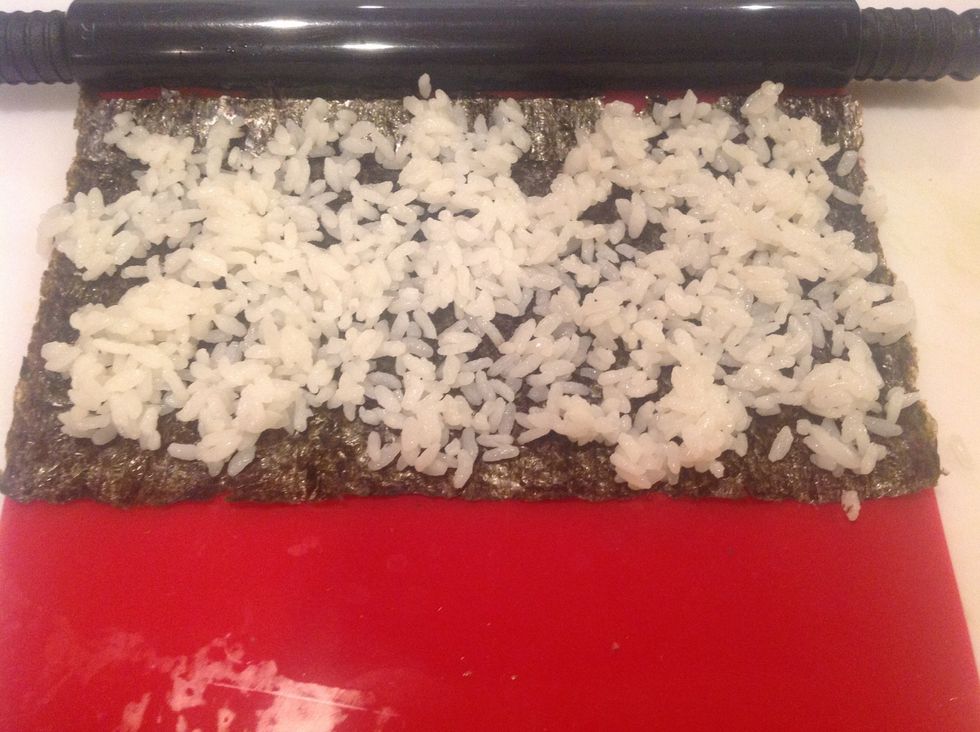 Take less than a handful of rice and spread it across the nori sheet