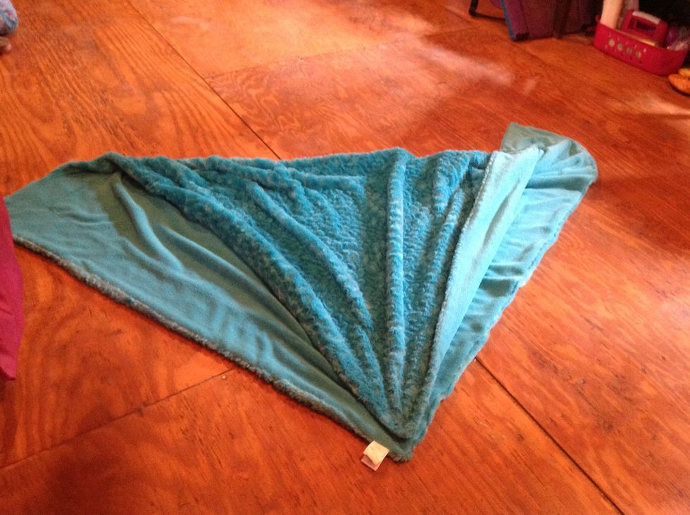 Take one corner of the blanket and bring it to the opposite corner.