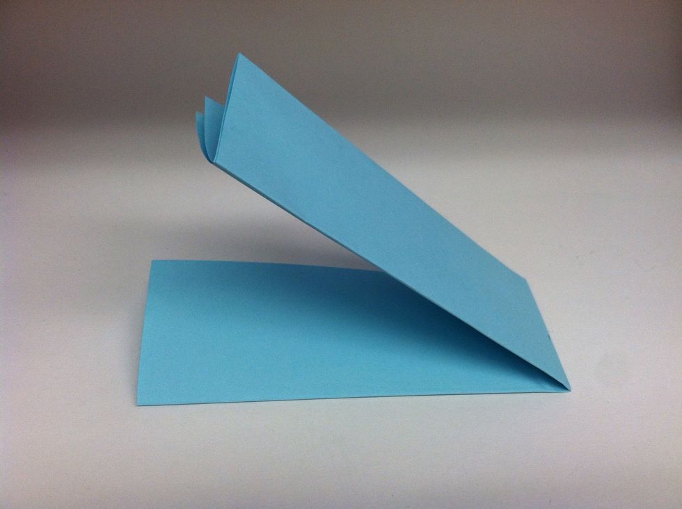 Take one end of the paper, and fold it over to meet the other end of the paper to make a crease.