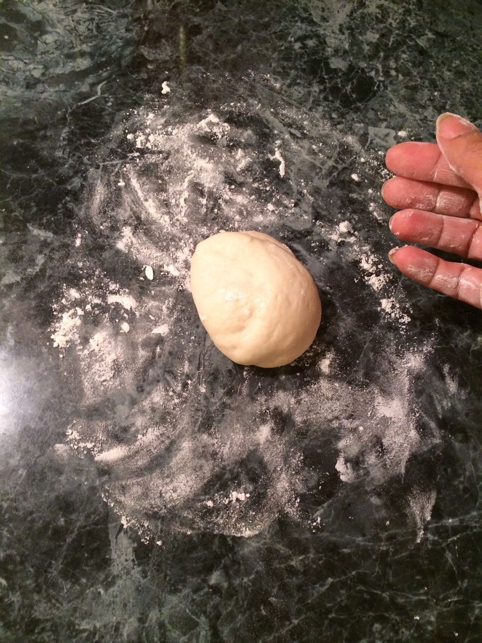 Take one of the dough balls and place it on the floured surface. Keep the other dough balls covered.