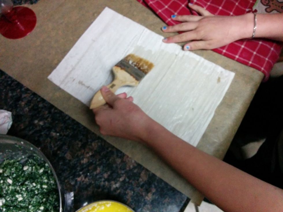 Take one sheet of phyllo dough and brush it with the melted butter.  Fold the sheet in half and brush it again.  Fold it in half one more time and brush with butter