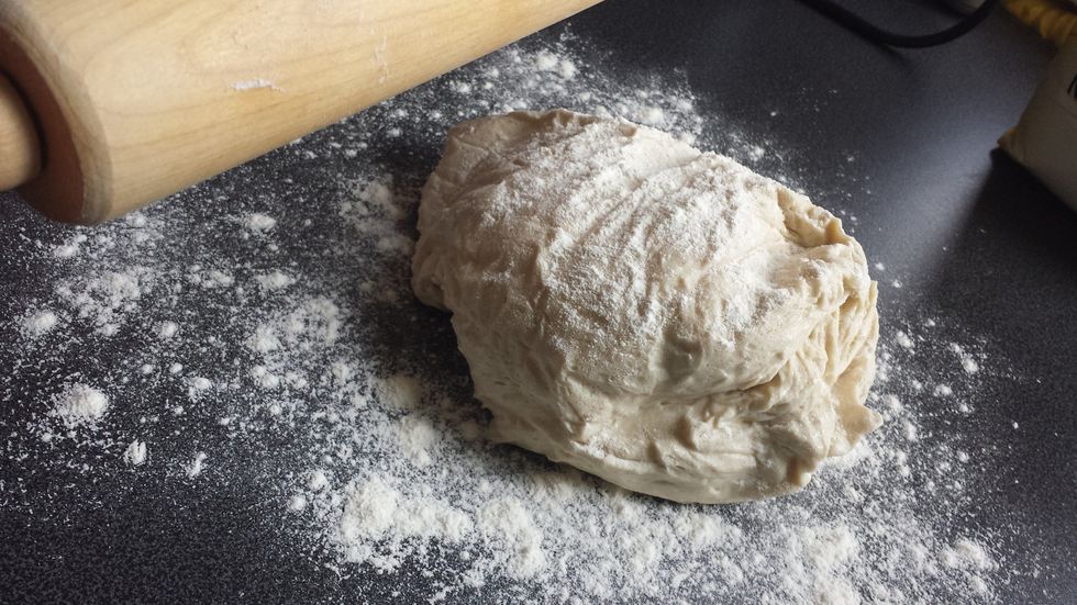 Take out rolling pin after that take one pizza dough out of bag and place on counter on flour. Then roll pizza dough in to one big circle (no holes in the circle).Using rolling pin.