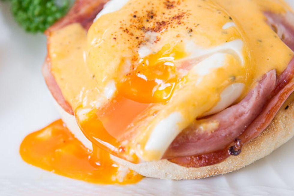 Take out the boiled potato and place it on a white flat plate. Then place the other ingredients in the order: fried ham, spinach and place poached egg on top. Pour cheese sauce on.