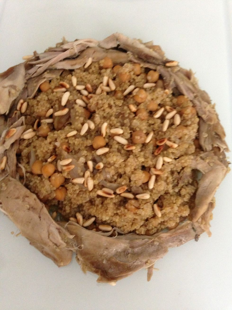 Take out the chicken separate the from the bones and make them into bite sizes. Serve the quinoa and the chicken pieces around. Decorate with pine seeds and little parsley for the Mediterranean look